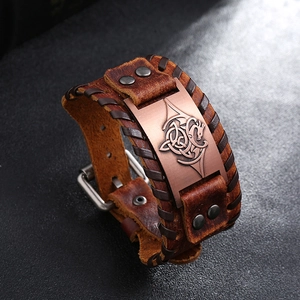 Détail d'un bracelet en cuir marron vintage avec motif dragon celtique et bords tressés