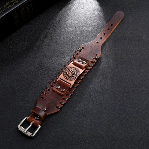 Detalle de pulsera de cuero trenzado vintage con emblema metálico del árbol de la vida