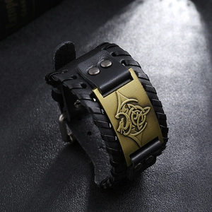 Détail d'un large bracelet en cuir noir avec plaque métallique de dragon celtique