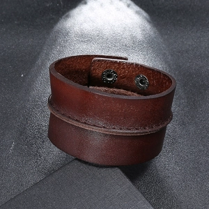 Detail of dark brown leather bracelet featuring vintage texture and double metal snaps