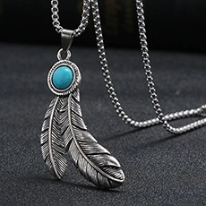 Détail macro d'un collier pendentif plume argenté rétro avec une pierre turquoise ronde