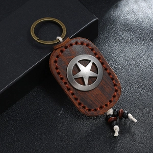 Close-up of vintage brown leather keychain with star metal emblem and beaded tassels