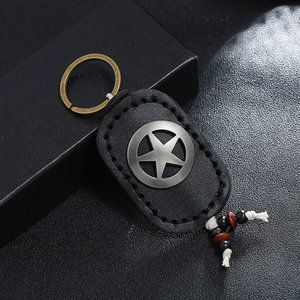 Handmade leather keychain with a vintage metal star and wooden beads on a black surface