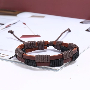 Détail d'un bracelet multicouche en cuir tressé avec des cordes texturées et un cordon réglable