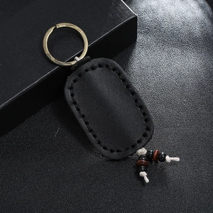 Close-up of black vintage leather keychain with hand-stitched edges and bronze metal ring