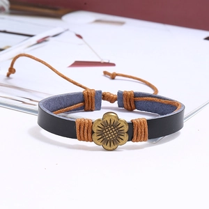 Détail d'un bracelet vintage en cuir noir avec un charm tournesol en métal de couleur bronze