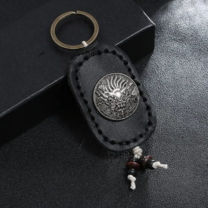 Retro handmade black leather keychain with silver dragon emblem and woven accents