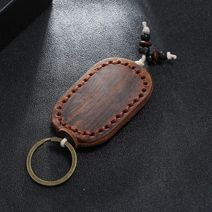 Hand-stitched vintage oval leather keychain with wood grain texture and bronze ring