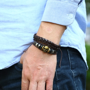 Detail of vintage multilayer leather bracelet with bronze skull charm and braided texture