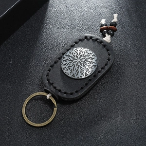 Macro shot of retro black leather keychain with silver embossed mandala metal plate