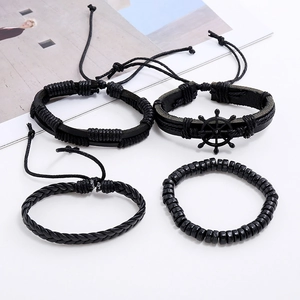 Macro detail of a four-piece black leather bracelet set featuring a vintage ship rudder charm