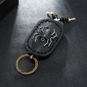 Detailed close-up of a retro leather keychain with a metallic spider and bronze ring