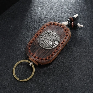Detail of vintage handmade brown leather keychain with metal relief and wooden beads