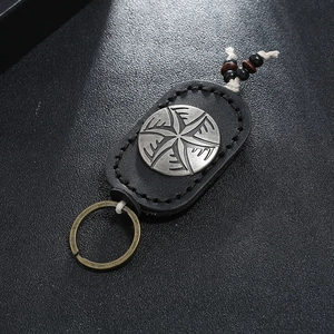 Close-up of vintage leather keychain with engraved silver medallion and wood bead details