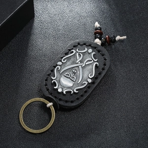 Detail of vintage leather keychain featuring hand stitching and a metal skull relief design