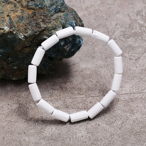 Macro detail van witte cilindrische kralen op elastische armband met matte afwerking