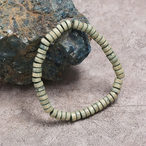 Retro grijsgroene houten kralenarmband getoond op een natuurlijke blauwe mineraalsteen