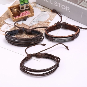 Détail d'un ensemble de bracelets vintage en cuir marron avec breloque plume pour hommes