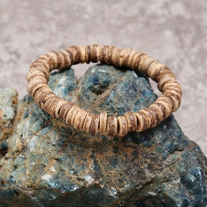 Macro detail of natural coconut shell beaded bracelet on rustic blue mineral stone background