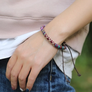 Bohemian colorful woven bracelet with adjustable cord on a female wrist in daylight