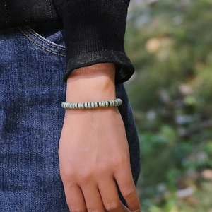 Boheems kralenarmband met groene schijfkralen om de pols van een model gedragen