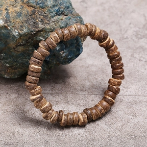 Macro detail of natural coconut shell beads with vintage wood grain on stone surface