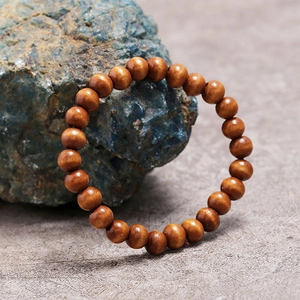 Primer plano de pulsera de cuentas de madera marrón oscuro sobre una piedra natural