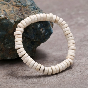 Pulsera elástica de cuentas de madera de hueso minimalista con textura natural sobre piedra