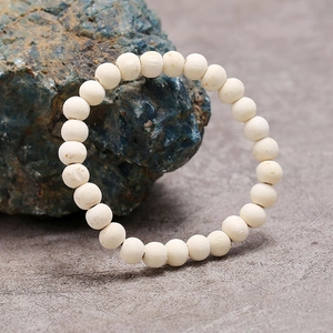 Vista detallada de la pulsera de cuentas de madera beige sobre piedra natural oscura