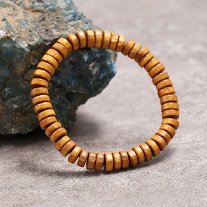 Primer plano detallado de la pulsera de cuentas de madera natural con textura sobre piedra