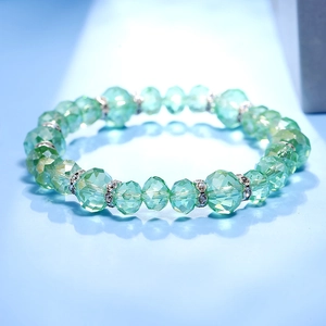 Detalle macro de cuentas de cristal verde claro facetadas con espaciadores de plata