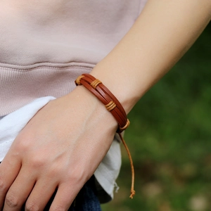 Retro brown woven leather bracelet for women with yellow cord wrap on a model wrist