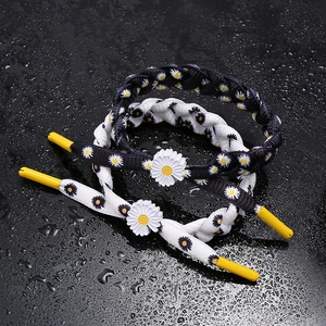 Close-up of woven daisy bracelets in black and white colors on a dark surface