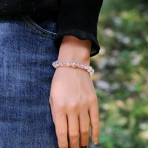 Pulsera minimalista de cuentas de cristal rosa con dijes de plata usada en la muñeca