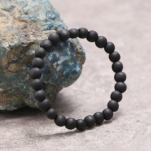 Primer plano de pulsera minimalista de cuentas de madera negra sobre fondo de piedra natural