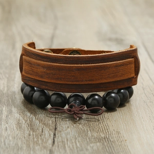 Retro men's jewelry set with brown leather cuff and wooden beaded bracelet on wood background