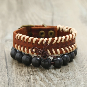 Retro brown leather cuff and black wooden bead bracelet set for men on wood background