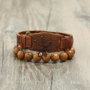 Detail of vintage brown leather strap and textured wooden bead bracelet set on wood