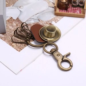 Detail of vintage bronze cowboy hat keychain with leather trim and four hooks on a desk