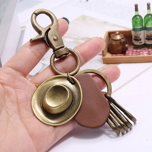 Vintage bronze cowboy hat keychain with leather tag and multi-ring clasp in hand