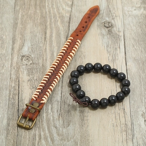 Retro brown leather cuff and black wooden bead bracelet set on a light wood background