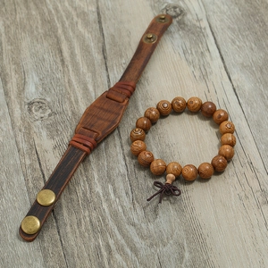 Men's vintage leather bracelet and natural wood bead set on a rustic gray background