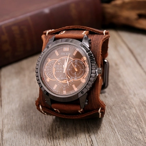 Macro shot of dark brown wide leather wristband watch with vintage metallic case on wood