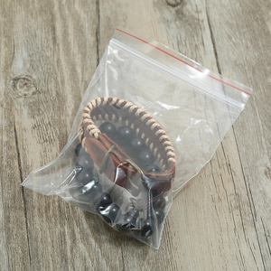 Detail view of vintage brown leather strap and black beaded bracelet set in packaging