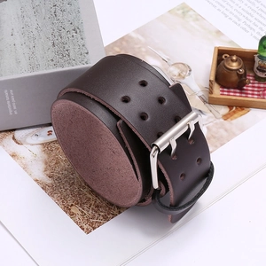 Detail view of dark brown wide leather bracelet featuring a silver double-pin metal buckle