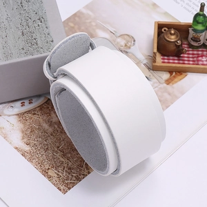 Detailed view of white wide leather bracelet with fine grain texture on a magazine