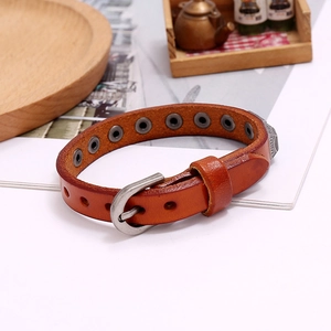 Detail of retro leather bracelet with silver buckle and embossed patterns on wood