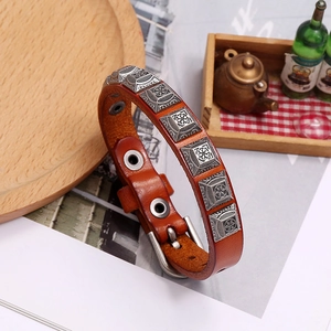 Detail view of retro brown leather bracelet with carved silver square metal studs