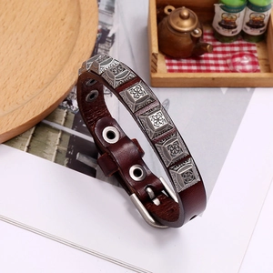 Close-up of brown leather punk bracelet with engraved silver pyramid studs and buckle