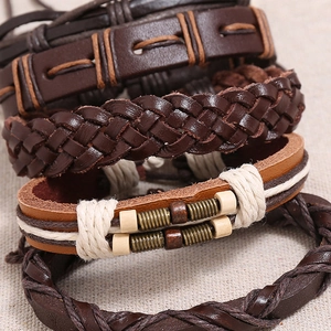 Close-up of multilayer leather bracelets set featuring braided cords and vintage textures
